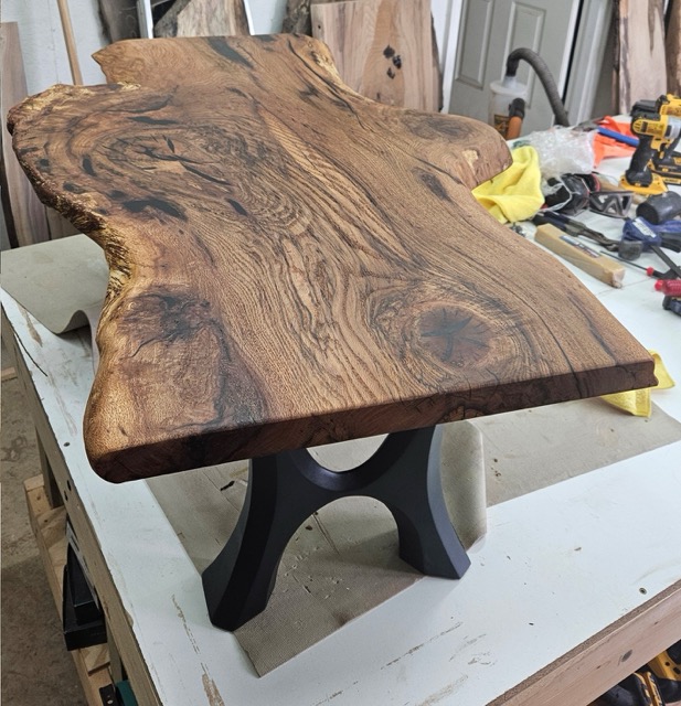A stained slab of wood coffee table with black legs.