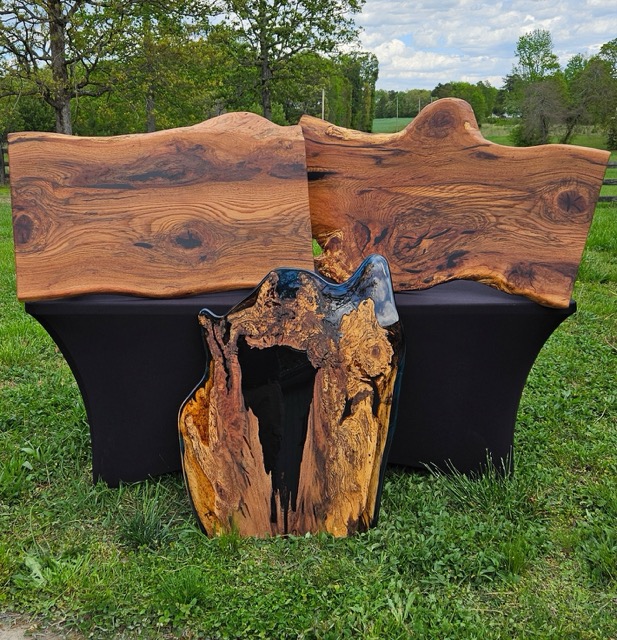 Two large stained slabs of wood and one live edge piece of wood with blue epoxy around the edges.